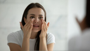 Woman looking in the mirror at her skin after microneedling in Plano, TX